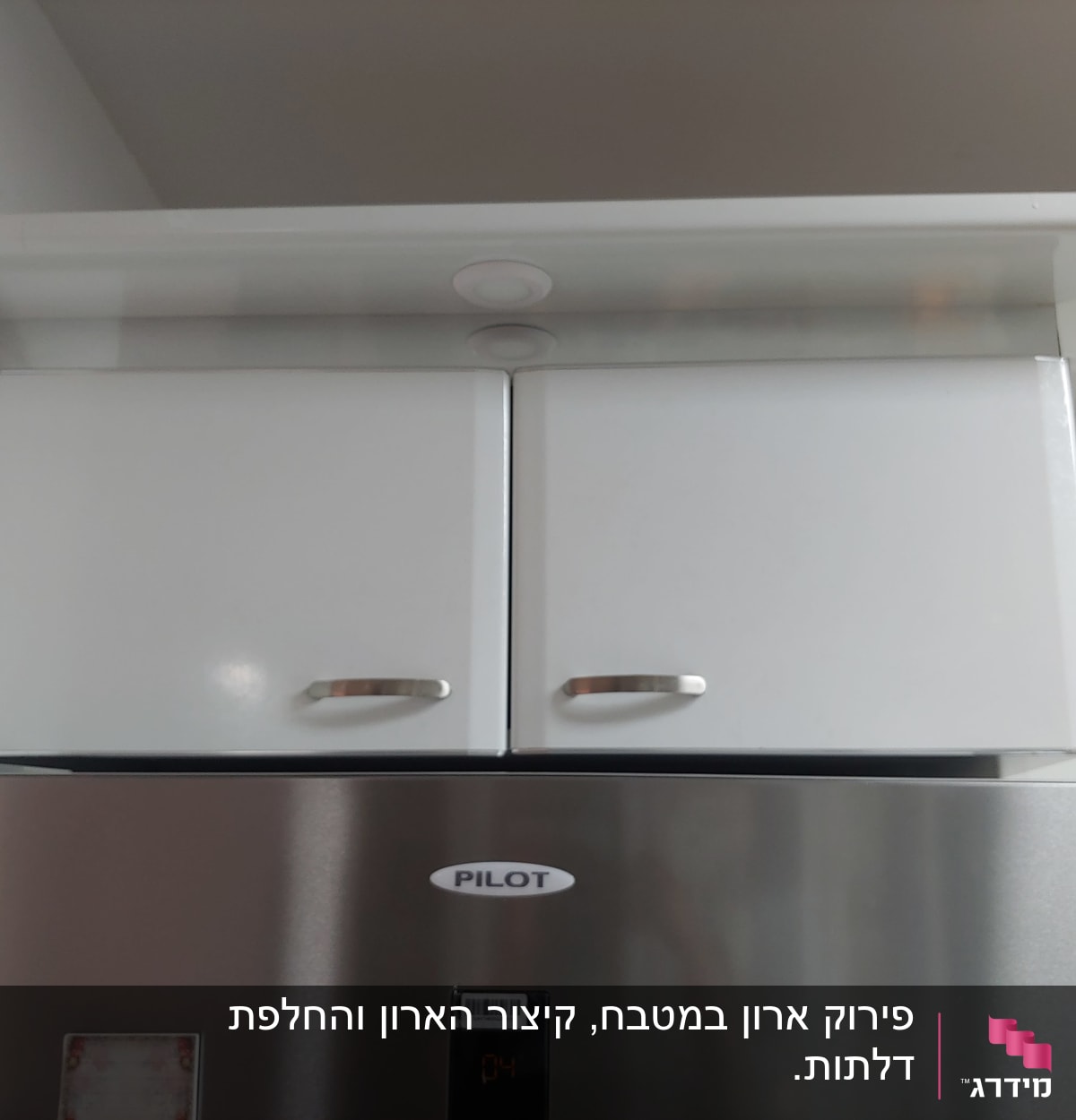 ארון מטבח לבן עם ידיות מתכת מעל מקרר